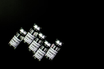 Coronavirus vaccine bottle flipped isolated on black background. Covid-19 situation disease pharmacy in laboratory and drug to cure people.  Healthcare and Medical concept. Development of research.