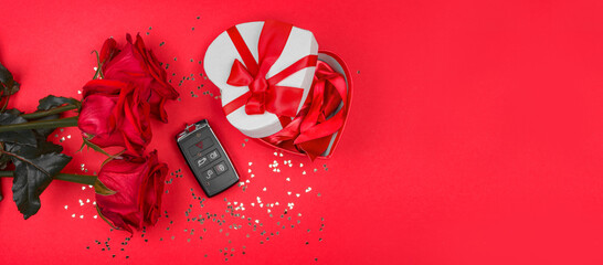 black car keys, red roses, a heart-shaped gift box with a red ribbon lie on a red background with a scattering of small hearts. Woman's, Valentine's Day gift concept. Flat lay, top view, banner. - Powered by Adobe