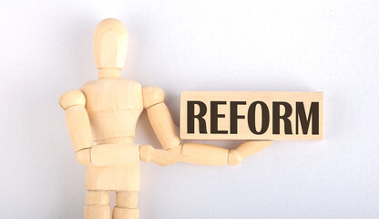 Wooden man shows with a hand to block with text REFORM