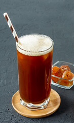 Iced coffee in tall glasses made with coffe ice cubes served with additional ice in glass bowl