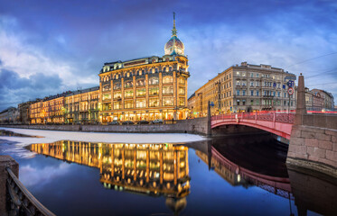 Esders and Scheufals store building and reflection in the water of the Moika River in St. Petersburg. Caption: Shop at the Red Bridge, Esders and Schefals