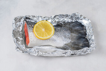 Fresh raw salmon fillet tail part with lemon on a light background. Pescatarian food menu, recipe....