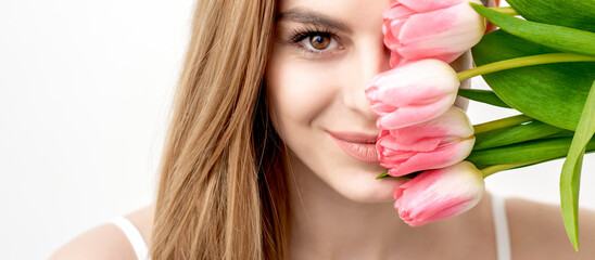 Portrait of a happy young caucasian woman with pink tulips against a white background