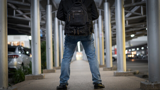 The back image of a young man standing on his way to a shopping mall in the late night.