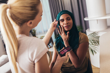 A make-up artist makes up a Muslim woman at home.