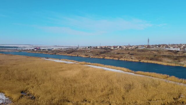 Frozen winter river near highway with moving heavy truck under blue sky. Cold season
