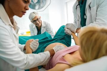 Fototapeta premium Pregnant woman pushes to give birth in hospital, obstetrician doctor assisting