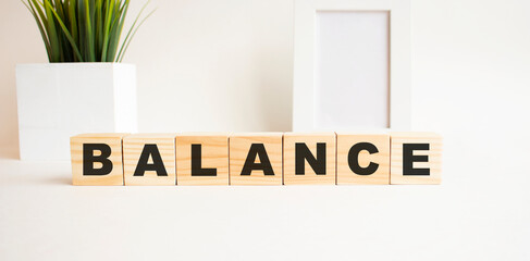 Wooden cubes with letters on a white table. The word is BALANCE. White background.
