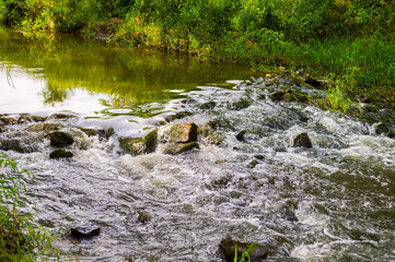 River flow over rocks in summer day. Waves of the river flow. Relaxing nature landscape scenics