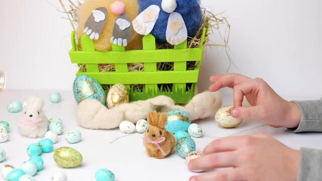 child hand palying with colorful easter eggs, green bucket with fluffy bunny, slow motion
