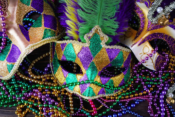 A group of Venetian and New Orlean Mardi gras mask with colorful beads on dark background