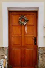 Colorful wooden beautiful entrance yellow door with a decorative Christmas holiday wreath of fir...
