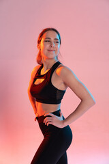 Obraz premium Sportive young woman holds her hands waist and poses with satisfied face.