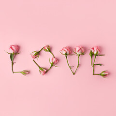 Word Love made with rose flowers and petals on pink background. Modern Valentine's Day, dating, romantic or love concept. Creative greeting card layout. Flat lay, top view.