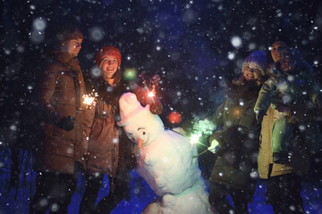 Fototapeta na wymiar group of friends with snowman sparklers party, christmas night and happy new year
