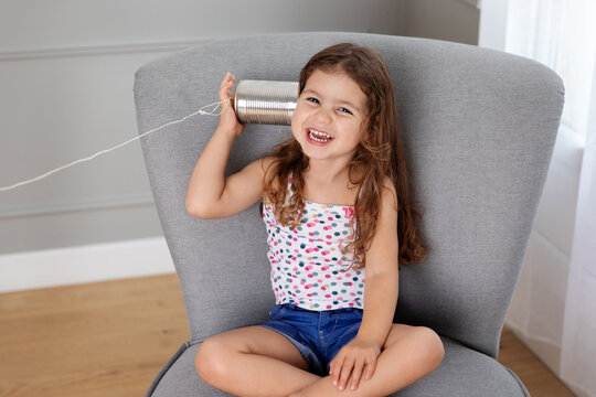 Happy young girl listening to tin can telephone