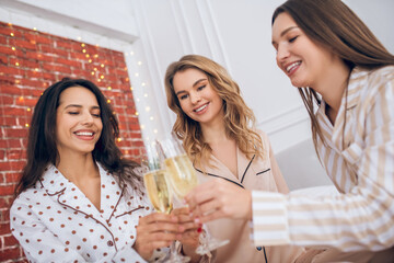 Three young girls having pajama party and drinking champagne