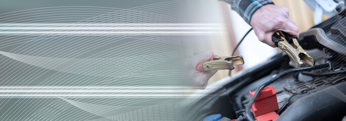 Hands of car mechanic using car battery jumper cable; panoramic banner