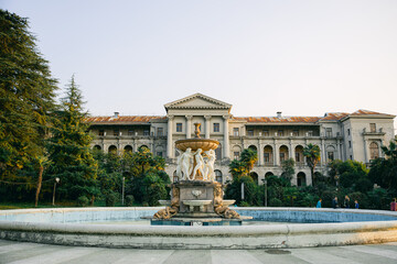 Naklejka premium Abandoned sanatorium named after Ordzhonikidze in the middle of the tropical jungle at sunset. View of the fountain and the main building among the trees.