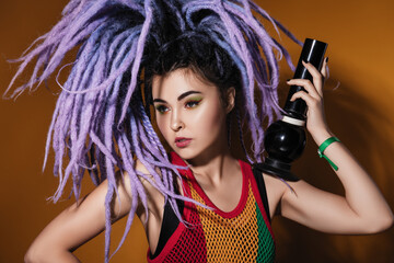 closeup studio portrait of a beautiful young woman with violet dreadlocks, color make-up, in a...
