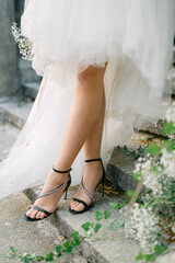 White wedding dress on the bride. Graceful shoes on his wife's feet. Gypsophila flowers on the stairs. White wedding decor