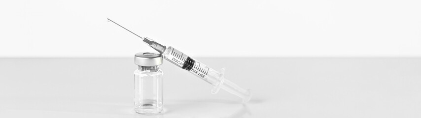 Syringe and vial with coronavirus vaccine, injection vial dose on a gray background. Prevention, medical concept, covid-19 immunization.