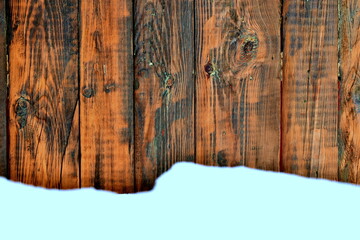 snow and a wall of dark wooden boards