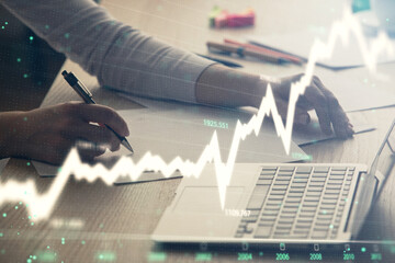 Double exposure of businesswoman hands typing on computer and forex chart hologram drawing....