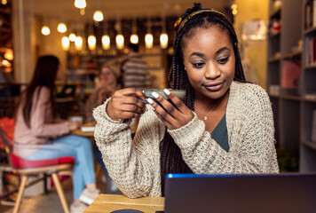 Portrait of young African woman using laptop in coffee shop.