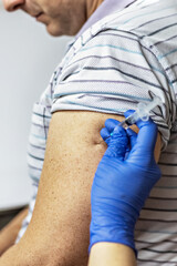 A doctor vaccinates a man against coronavirus at a clinic. Close-up. The concept of vaccination,...