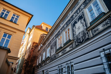 Fascinating narrow picturesque street Jansky vrsek with baroque and renaissance historical house richly decorated with sgraffito, sunny day at Lesser Town, Prague, Czech Republic