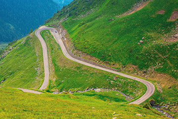 road in high mountains of romania. popular travel destination of fagaras ridge. route 7c is also known as transfagarasan. dramatyc summer weather with clouds on the sky