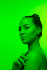 Inspired. Handsome woman's portrait isolated on green studio background in neon light, monochrome. Beautiful female model. Concept of human emotions, facial expression, sales, ad, fashion and beauty.