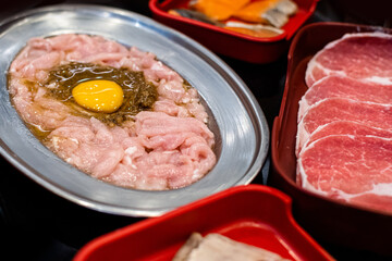 peper herb marinated sliced pork topped with egg yolk prepare for sukiyaki