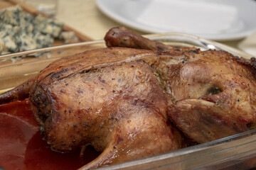 There's a roast duck on a platter on the dining table, close-up, selective focus. Concept: Christmas duck, family dinner or holiday dinner.