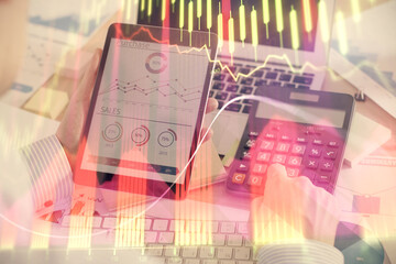 Double exposure of man's hands holding and using a digital device and forex graph drawing. Financial market concept.