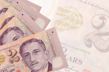 2 Singaporean dollars bills lies in stack on background of big semi-transparent banknote. Abstract...