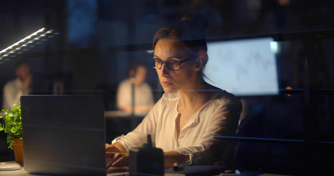 Young businesswoman working on computer in office at night.