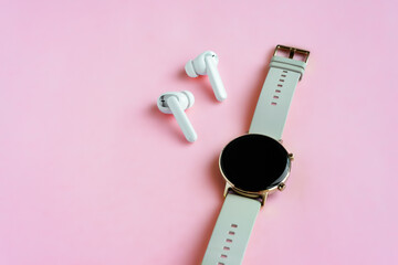 Wireless headphone and smartwatch on pink background