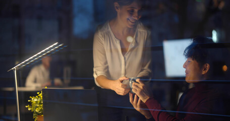 Businesswoman bringing coffee to colleagues working together at night in office
