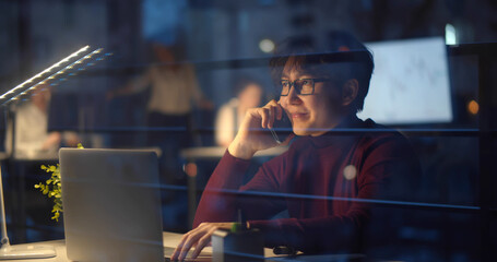 Businessman talking on phone with colleague discussing project sitting in office late in evening