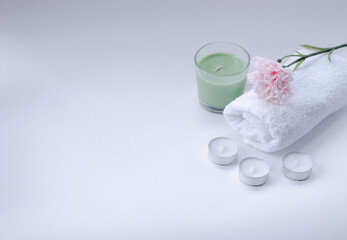 white, terry towel with a pink flower on top and candles on a white background