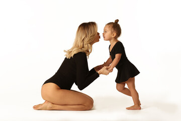 cute baby girl and mum in black bodies having fun full body studio portrait