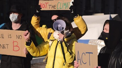 A group of people with banners and a megaphone in hand are protesting in the city square for save planet clean world act now  