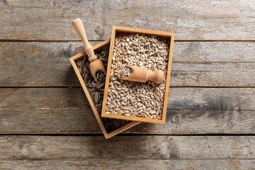 Boxes and scoops with sunflower seeds on wooden background