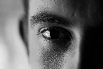 Expressive strong look - closeup of an eye looking sad and empty, high contrast black and white shot