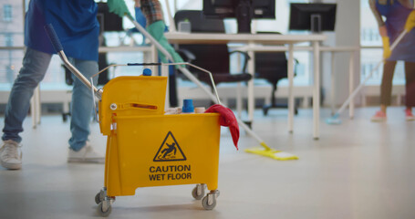 Cropped shot of janitors with mop cleaning modern office floor