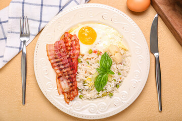 Plate with tasty egg, bacon and rice on color background