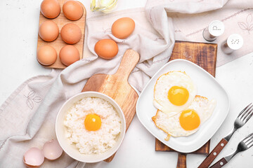 Plate with tasty eggs and rice in bowl on light background