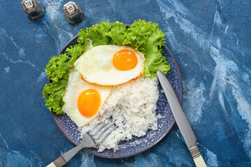 Plate with tasty eggs and rice on color background